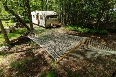 a trailer is parked in the woods next to a tent at The Outlier Inn in Woodridge