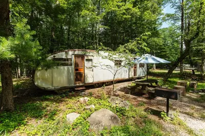 an old trailer in the woods with an umbrella at The Outlier Inn in Woodridge