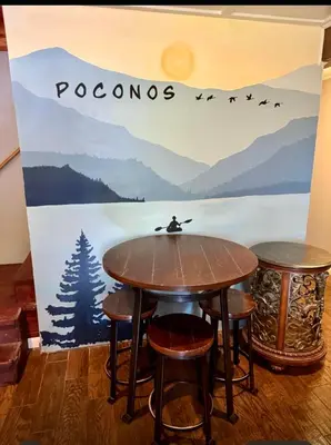 a table and stools in front of a wall with the word poconos at Haven View Retreat in White Haven