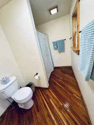 a bathroom with a toilet and a wooden floor at Cammalot - Pine Creek Valley
