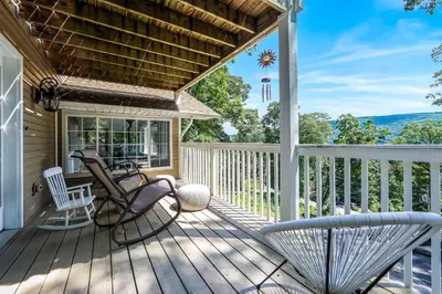 a porch with rocking chairs and a view of the mountains at Zen Lake House in Greenwood Lake