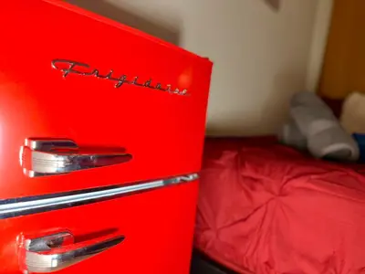 a red refrigerator sitting next to a bed at BP STAYS - Hotel-Style, No Host, Professionally Managed ID247 in Jersey City