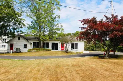 a white house with a red door and a yard at Pocono Ridge Inn East Stroudsburg - Poconos in East Stroudsburg