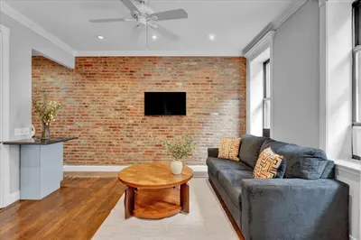 a living room with a couch and a brick wall at Stylish 3BR-2BA in Gramercy -Modern & Central in New York