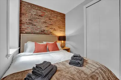 a bedroom with a bed with a brick wall at Stylish 3BR-2BA in Gramercy -Modern & Central in New York