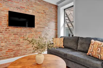 a living room with a couch and a brick wall at Stylish 3BR-2BA in Gramercy -Modern & Central in New York