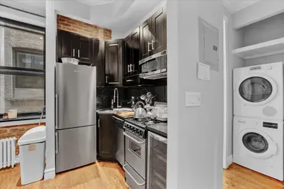 a kitchen with a refrigerator and a washer and dryer at Modern 2BR with Private Garden In Gramercy Park in New York