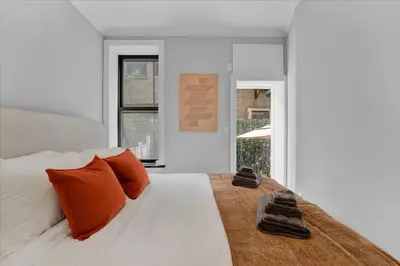 a bedroom with a white bed with orange pillows at Modern 2BR with Private Garden In Gramercy Park in New York