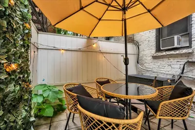 a table and chairs with an umbrella on a patio at Modern 2BR with Private Garden In Gramercy Park in New York