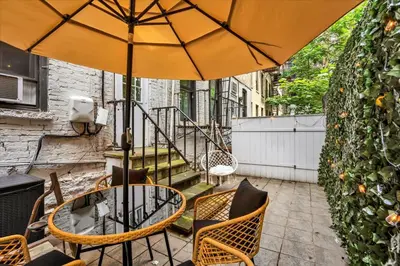 a patio with a table and chairs and an umbrella at Modern 2BR with Private Garden In Gramercy Park in New York