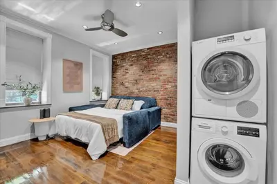 a bedroom with a bed and a washing machine at Stylish 3BR-2BA in Gramercy in New York