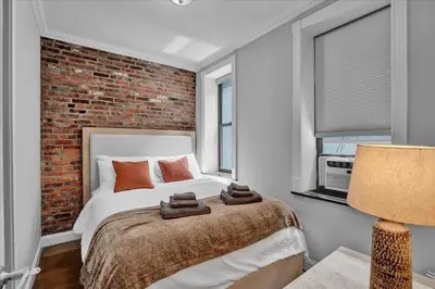 a bedroom with a bed and a brick wall at Stylish 3BR-2BA in Gramercy in New York