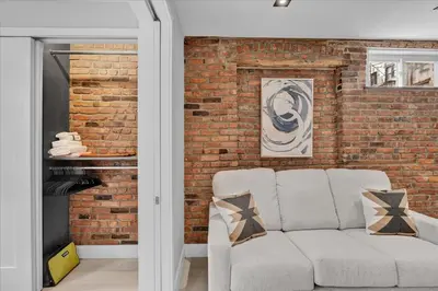 a living room with a brick wall and a couch at SoHo Designer 2BR w balcony in New York