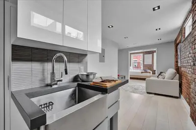 a kitchen with a sink and a living room at SoHo Designer 2BR w balcony in New York