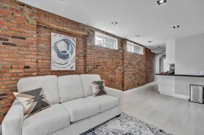 a living room with a brick wall and a couch at SoHo Designer 2BR w balcony in New York
