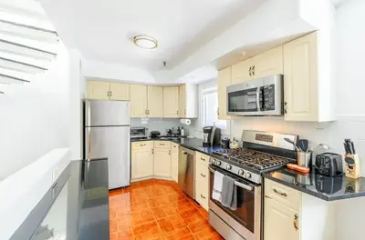 a kitchen with white cabinets and a stove top oven at Modern 3BR Townhouse with Private Rooftop & Parking Minutes to NYC in Hoboken