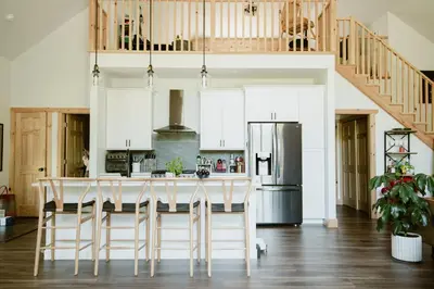 a kitchen with white cabinets and a kitchen island with bar stools at Luxe Modern Cabin with Pond, Fire Pit, Hiking, near Bethel Woods in Narrowsburg