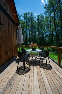 a patio with a table and chairs on a deck at Luxe Modern Cabin with Pond, Fire Pit, Hiking, near Bethel Woods in Narrowsburg