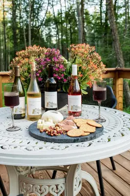 a table with wine bottles and a plate of food at Luxe Modern Cabin with Pond, Fire Pit, Hiking, near Bethel Woods in Narrowsburg
