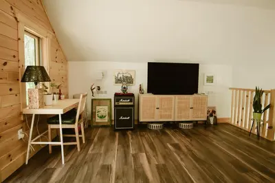 a living room with a flat screen tv and a table at Luxe Modern Cabin with Pond, Fire Pit, Hiking, near Bethel Woods in Narrowsburg