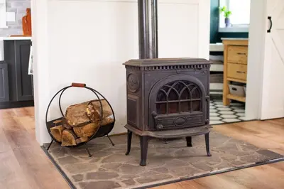a wood stove and a basket of logs on a rug at Fire Pit, Private & Stylish Birdsong Schoolhouse in Barryville