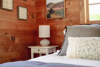 a bedroom with a bed and a lamp on a table at Fire Pit, Private & Stylish Birdsong Schoolhouse in Barryville