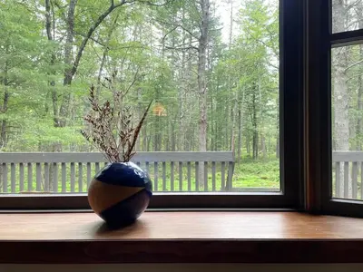 a vase sitting on a window sill in front of a window at Fire Pit Woodsy & Private - Cabin on Woods Road in Yulan