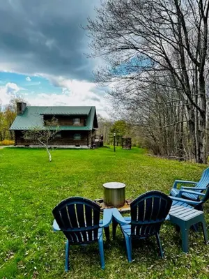 two chairs and a table in a yard with a house at Fire Pit, BBQ & Sprawling Lawn Elk Point Cabin in Livingston Manor