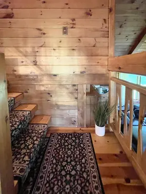 a room with wooden walls and benches and a rug at Fire Pit, BBQ & Sprawling Lawn Elk Point Cabin in Livingston Manor
