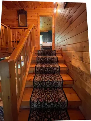 a staircase in a cabin with wooden walls and wooden floors at Fire Pit, BBQ & Sprawling Lawn Elk Point Cabin in Livingston Manor