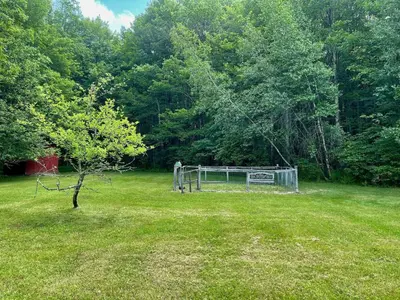 a field with a fence and a tree in the grass at Fire Pit, BBQ & Sprawling Lawn Elk Point Cabin in Livingston Manor