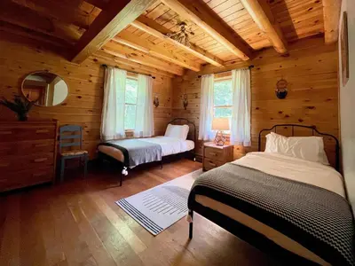 a bedroom with two beds in a log cabin at Fire Pit, BBQ & Sprawling Lawn Elk Point Cabin in Livingston Manor