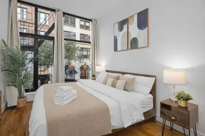 a white bedroom with a large bed and windows at Stylish Manhattan Escape in Prime Spot in New York