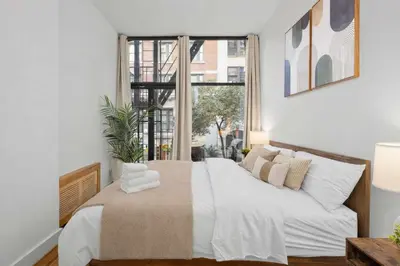 a bedroom with a bed with white sheets and a window at Stylish Manhattan Escape in Prime Spot in New York
