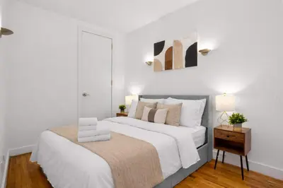 a white bedroom with a large bed and a table at Stylish Manhattan Escape in Prime Spot in New York