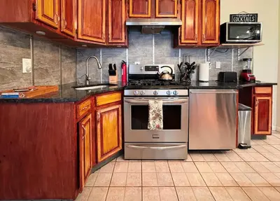 a kitchen with wooden cabinets and a stainless steel stove at New York Skyline One of a Kind View in Union City
