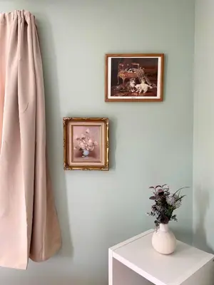 a wall with two pictures and a vase on a table at Fern Hollow Home
