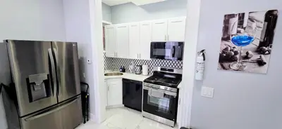a kitchen with a stainless steel refrigerator and white cabinets at Newly Renovated 2B 2BA apt! mins to PATH & NY! in Jersey City