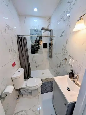 a white bathroom with a toilet and a sink at Newly Renovated 2B 2BA apt! mins to PATH & NY! in Jersey City