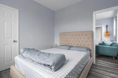a white bedroom with a bed and a blue chair at Two BR near Metlife with Laundry & Parking in Lodi