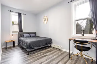 a bedroom with a bed and a desk and two windows at Three BR near Metlife with Laundry & Parking in Lodi