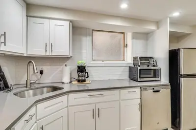 a kitchen with white cabinets and a sink and a microwave at Walk to Hudson River Parks Recently Renovated Apt in Hoboken