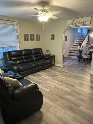 a living room with a black leather couch and a staircase at Cozy 1 BR Retreat within walking distance to all the Hershey Attractions in Hershey