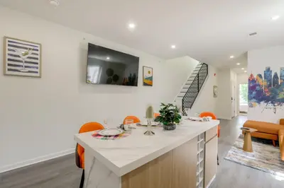 a kitchen with a white counter and orange chairs at Penthouse Condo with Rooftop Deck in Philadelphia! in Philadelphia