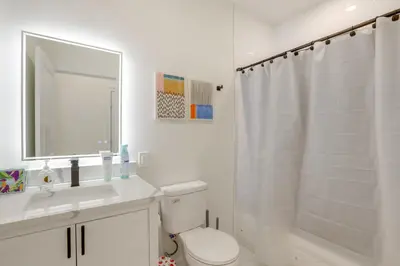 a white bathroom with a toilet and a sink and a mirror at Penthouse Condo with Rooftop Deck in Philadelphia! in Philadelphia