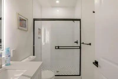 a white bathroom with a shower and a toilet at Penthouse Condo with Rooftop Deck in Philadelphia! in Philadelphia