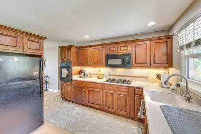 a kitchen with wooden cabinets and a stainless steel refrigerator at Near Dtwn Harrisburg Stylish Home with Patio and Yard in Camp Hill