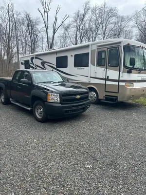 a black truck parked next to a trailer and an rv at Art Rv motorhome in Quakertown