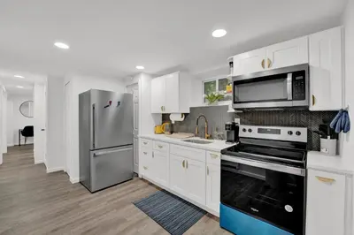 a kitchen with white cabinets and a stainless steel refrigerator at Cozy Garden 1Bed Apt, Lincoln Park in Jersey City