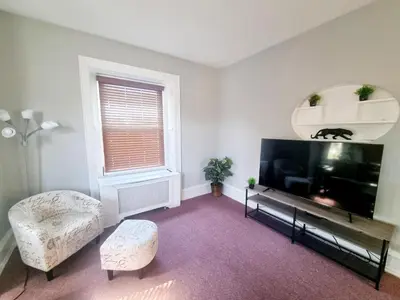 a living room with a flat screen tv and a chair at Cozy & Inviting A Place to Call Home in Melrose Park
